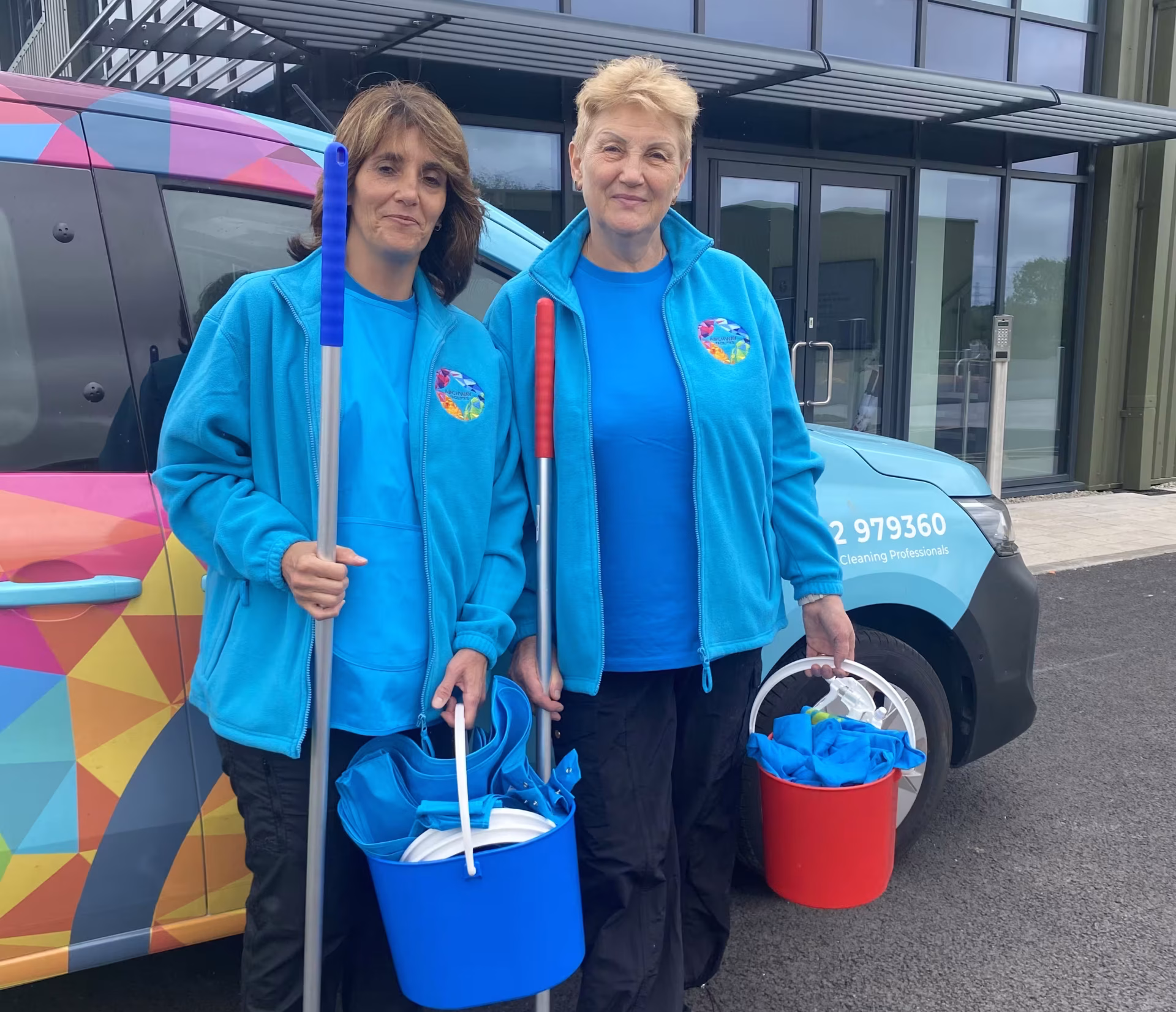 Two Archway Facilities cleaners with cleaning equipment outside a commercial building.